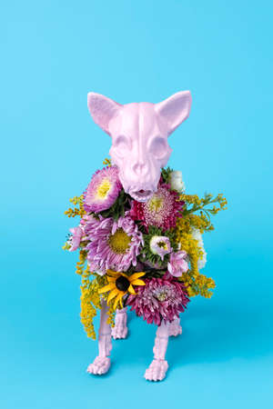 Pink animal skeleton with colorful flowers on pink background. Minimal Halloween scary concept. Isometric view photography.の写真素材