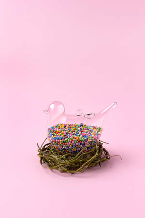 Minimal composition of transparent bird filled with candies sitting in  nest. Creative concept background.の写真素材