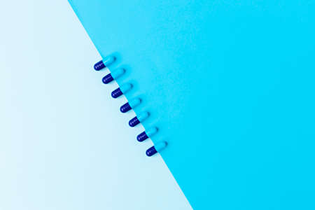 Heap of vivid blue capsule pills close up background. Creative layout of pills and capsules on blue background. Covid-19 or Coronavirus concept.の写真素材