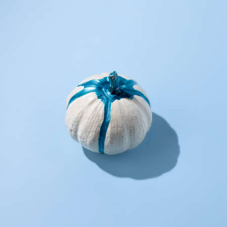 Miniature pumpkin with dripping color on blue background. Glamour Halloween. Autumn still life flat lay.の写真素材