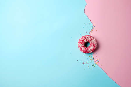 Delicious yummy pink glazed topping doughnut on dual-tone background. Minimal modern concept. Flay lat, aerial view pastel scene.の写真素材