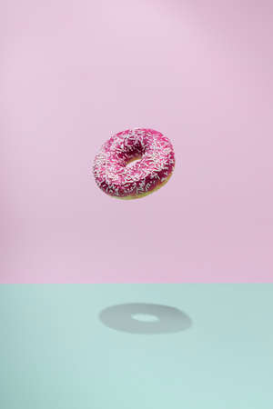 Donuts flying over a blue and pink background. Minimal bakery, baking concept. Levitation.の写真素材