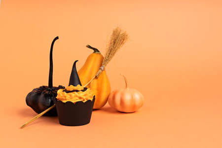 Creative layout made with pumpkins, muffin, witch broom and hat. Minimal Halloween concept. Copy...