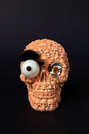 Orange skull with glass eye on black. Minimal gothic concept. Halloween creative background.の写真素材