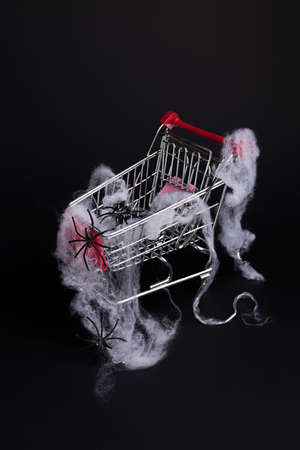 Creative layout made with spiders in shopping cart. Minimal Halloween shopping background. Invitation card, party, copy space.の写真素材