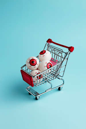 Eyeballs in shopping cart. Minimal Halloween background. Invitation card, party.の写真素材