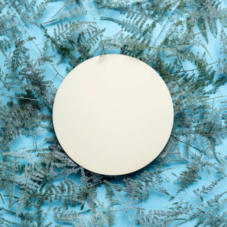 Creative layout made of frozen silver leaves with paper note on ice blue background. Minimal winter,...