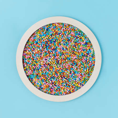 Party backdrop made circle frame and sprinkles on blue paper background. Minimal birthday, food, anniversary, candy or wedding concept. Flat lay, card design.の写真素材