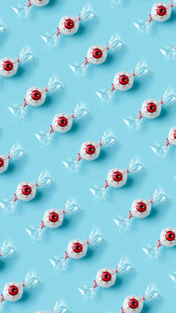 Creative pattern made with candy eyeballs on blue background. Minimal Halloween background....