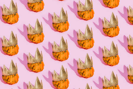 Fall pattern made of pumpkins with golden crown on a pink background. Autumn, Halloween or Thanksgiving concept. Trend shadow, flat lay, top view.の写真素材