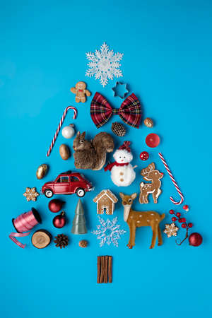 Christmas holiday decorative layout made with candy cane, ornaments, snowman, deer and gingerbread man on blue background. Minimal winter or New Year concept with copy space. Flat lay, top view.の写真素材