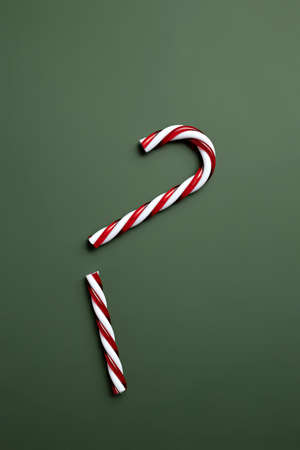 Broken candy cane on green background. Minimal winter or New Year seasonal concept. Flat lay.の写真素材