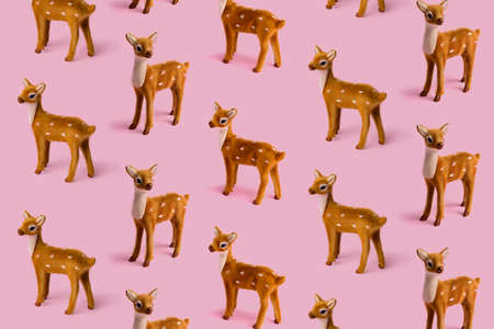 Christmas layout pattern made with reindeer toy on the bright pink background. Minimal New Year or winter season concept. Greeting card or banner.の写真素材
