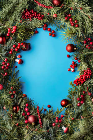 Christmas card background. Paper notice sheet with copy space for text. Decorative frame of fir branches and holly berries. Minimal winter or New Year seasonal concept. Flat lay, top view.の写真素材