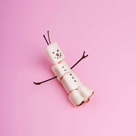Creative Christmas layout made with snowman marshmallow on pastel pink background. Minimal winter food concept. Top view, flat lay.の写真素材