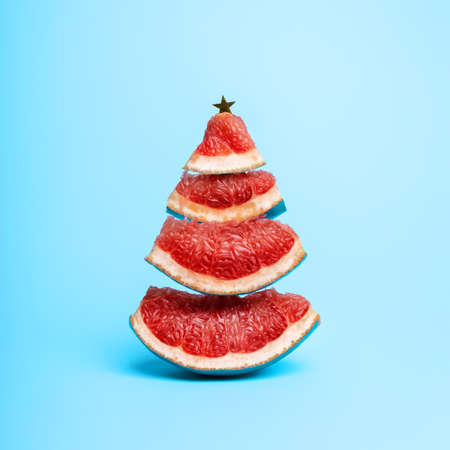 Christmas tree made with blue grapefruit slices on vibrant background. Minimal New year, winter food or drink concept.の写真素材