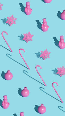 Modern Christmas pattern made with pink ornament, candy cane and snowflake on pastel blue...