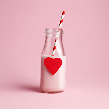 Valentines food layout made with milk bottle with heart and straw on pastel pink background. Minimal love, drink, or wedding concept.の写真素材