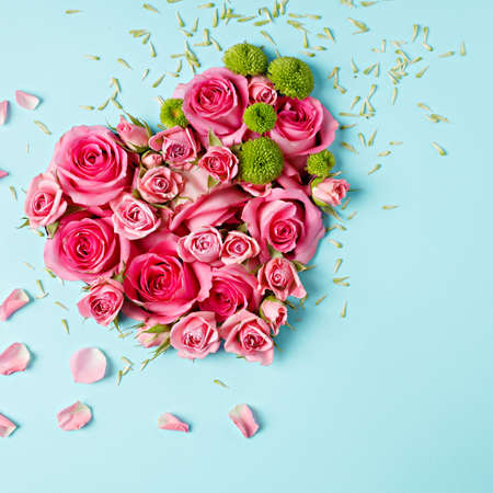 Heart shaped bouquet of beautiful fresh pink rose flowers on pastel blue background. Minimal Valentines Day, Easter, wedding or Mother's day concept. Creative spring or summer floral layout. Flat lay.の写真素材