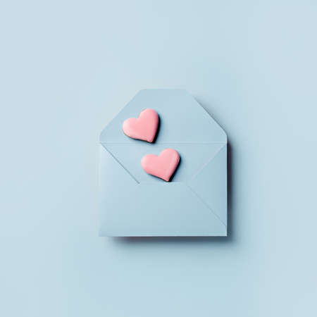 Love layout made with pink hearts coming out of blue envelope on pastel background. Creative...