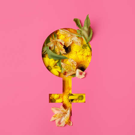 International Women's Day creative layout made with female symbol and colorful flowers on pink background. Minimal natural March 8th or feminism concept. Banner, flyer, or postcard. Flat lay.の写真素材