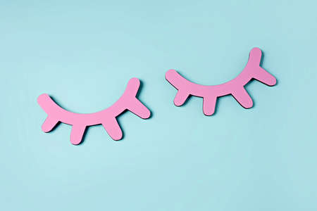 Creative layout with vivid pink eyelashes on pastel blue background. Minimal make up salon, beauty...