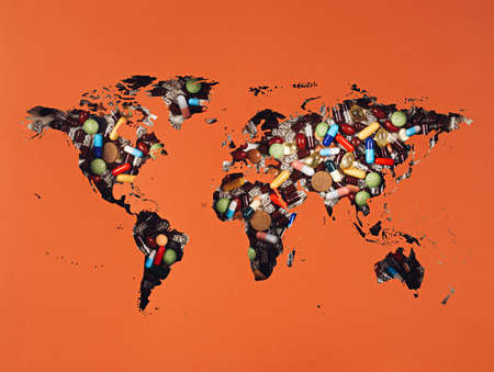 World map with pills and tablets on earthy orange background. pandemic minimal art concept. Creative...