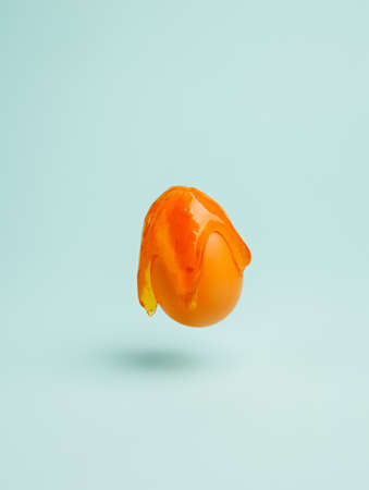Orange egg with slime against pastel green background. Creative Easter holiday or food concept. Abstract background.の写真素材