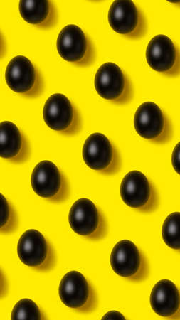 Easter pattern made with black painted eggs on vibrant yellow background. Minimal food concept. Flat lay.の写真素材