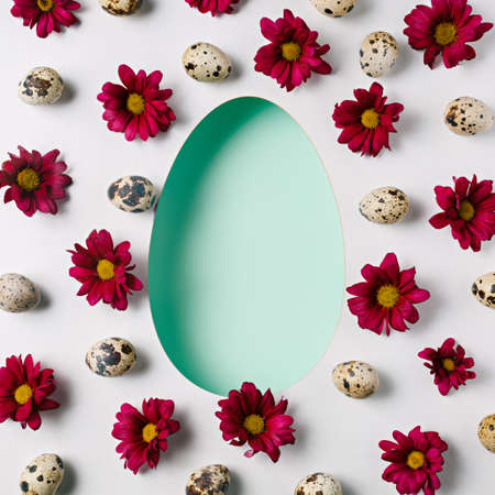 Easter card with egg shaped copy space surrounded with burgundy flowers and quail eggs. Creative...