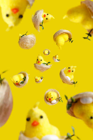 Many chicks explosion and free falling on vibrant yellow background. Creative Easter or animal concept. Selective focus, shallow depth of field.の写真素材