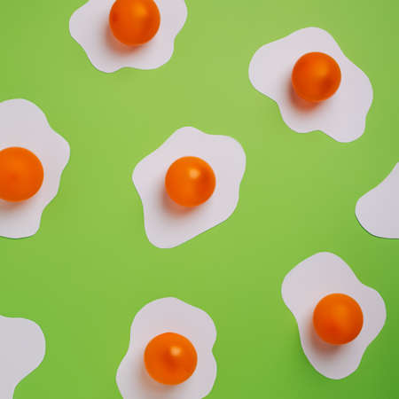 Fried eggs pattern made of paper on a vibrant green background. Minimalistic food fashion concept. Flat lay, top view.の写真素材