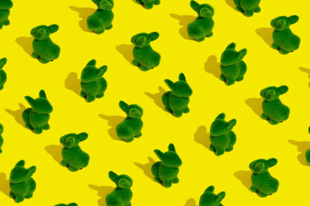 Many green bunny rabbits with summer shadows against vibrant yellow background. Minimal Easter pattern.の写真素材