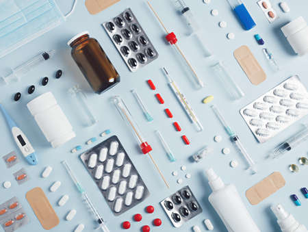 Pattern made with tablets blisters, pills, bottle, thermometer and syringe on bright white background. Creative pharmacy or medical industry concept. Flat lay, top view.の写真素材