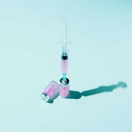 Syringe and vaccine bottle on blue background. Creative mass vaccination concept. influenza or flu...