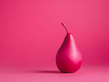 Pink painted pear isolated on vibrant pink background. Contemporary vegetarian fruit diet concept....