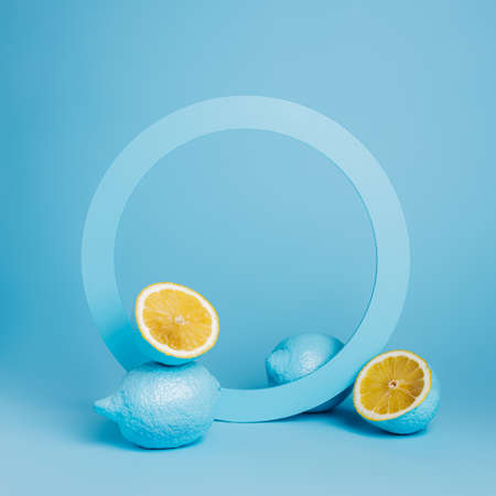 Product podium and frame for copy space with blue lemons on blue background. Concept scene stage showcase for juice, cocktails or fruit related products. Minimal summer empty mock up template.の写真素材