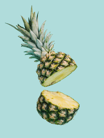 Pineapple sliced in half flying against pastel blue background. Minimal fruit food concept....