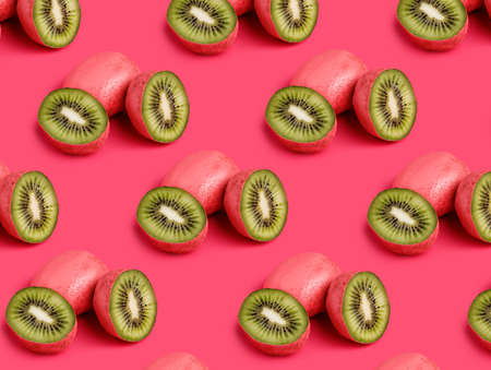 Pattern with pink kiwi sliced in half against matching pink background. Creative summer fruit...