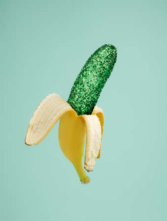 Surreal image of banana with sparkling green glitter on mint background. Creative food concept. Glamour pop art fashion aesthetic.の写真素材