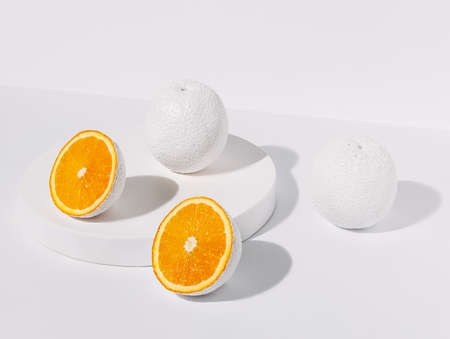 Oranges painted in white and cut into slices isolated on bright white background. Creative food concept. Monochrome trendy composition with ripe and juicy tropical fruit.の写真素材