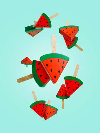 Flying watermelon ice creams on wooden sticks falling down isolated on bright turquoise background....