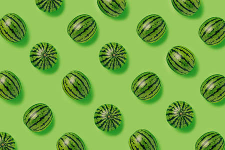 Geometrical pattern of fresh watermelons isolated on a bright green background. Creative food...