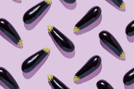 Geometrical pattern of eggplants isolated on pastel lilac lavender background. Abstract vegetable texture with summer shadows. Creative food concept. Flat lay, top view.の写真素材