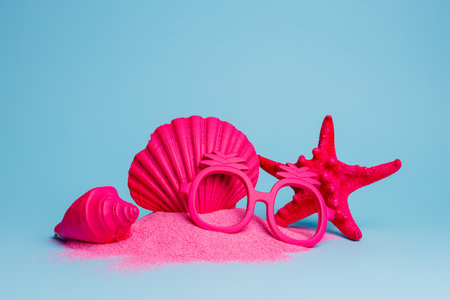 Summer scene with pink starfish, shell, nutmeg, and pineapple sunglasses on vibrant pink sand isolated on a bright blue background. Creative holiday concept. Tourism or tropical vacation arrangement.の写真素材