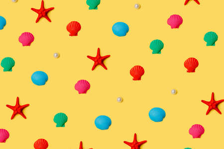 A pattern of beach souvenirs isolated on a yellow background. Colorful shells, starfish and pearls...