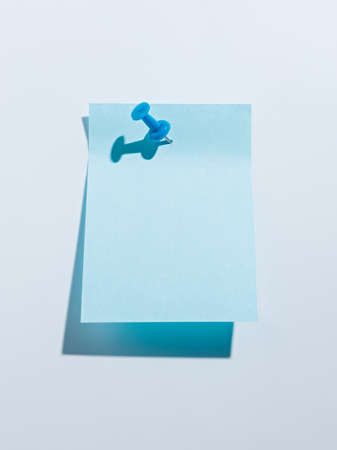 Blank blue sticky note pinned on a bright blue wall background. Office and task reminder. Creative work, school or meeting concept. Minimal aesthetic.の写真素材