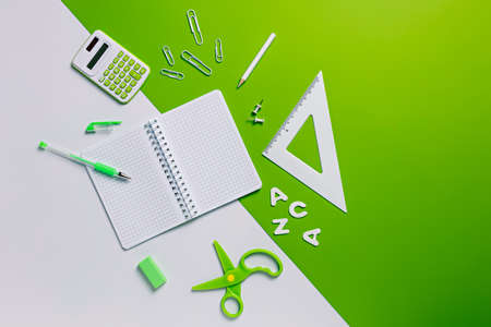 School and office stationery on two tone green and white background. Creative office or back to school concept. Blank note with copy space for text. Flat lay.の写真素材
