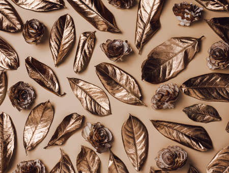 Fall texture with golden leaves rose flowers on a pastel beige background. Creative autumn season concept. Golden natural pattern. Flat lay.の写真素材