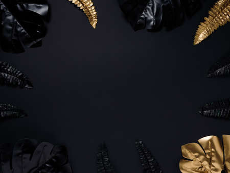 Black and gold tropical leaves on black background. Flat lay, top view.の写真素材